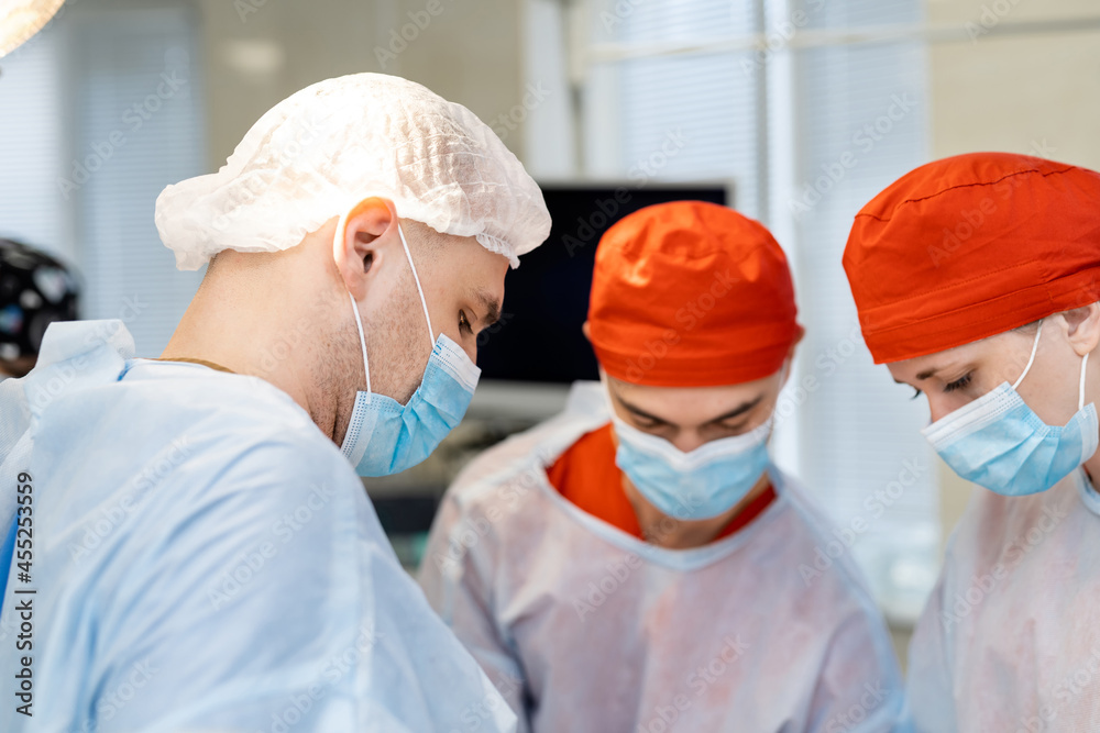 现代医院里戴着口罩的年轻医生外科医生。新诊所里的医疗外科工作者。