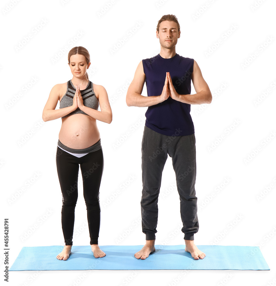 年轻孕妇和她的丈夫在白色背景下练习瑜伽