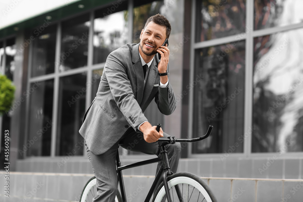 拿着手机的商人在城市街道上骑自行车