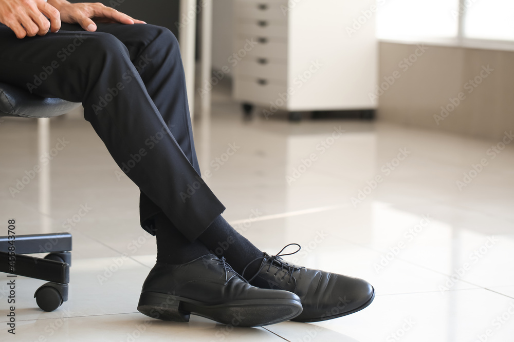 穿着现代鞋的商人在办公室的腿