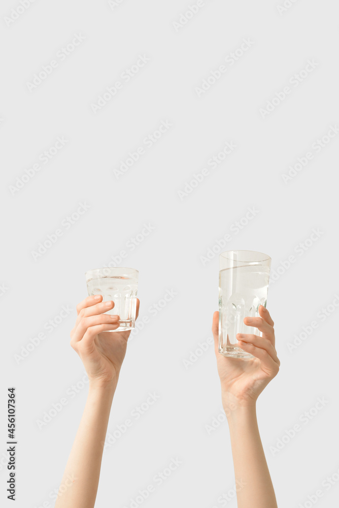 女性手拿着一杯水在浅色背景下