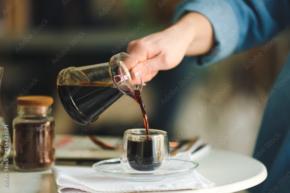 一名女子将土耳其热咖啡倒入餐桌上的玻璃杯中，特写镜头