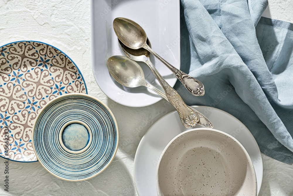 白色背景下的不同盘子、勺子和餐巾，特写