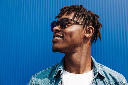 portrait of an african guy in sunglasses, on a blue background, model black guy in the city