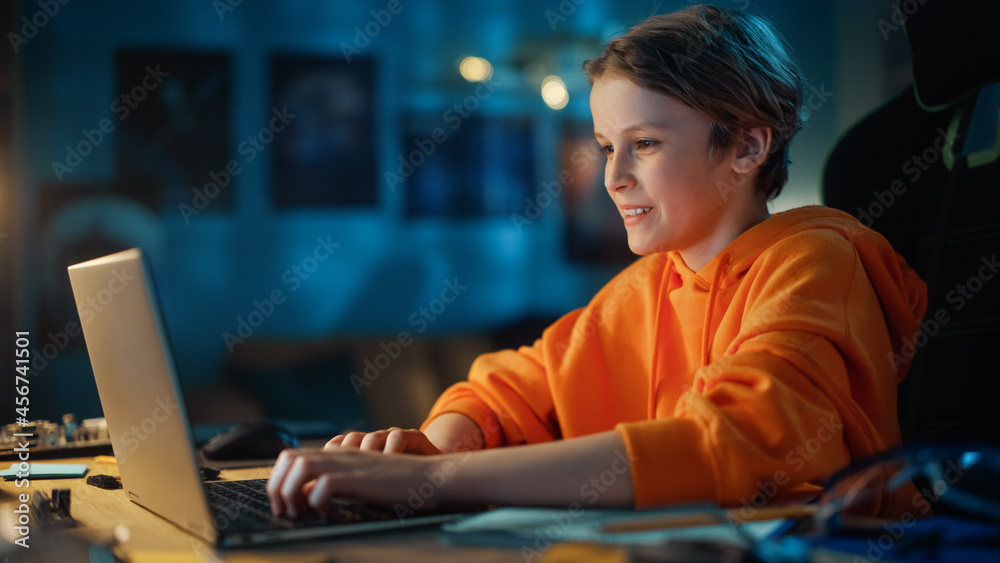 聪明的小男孩在家里舒适的暗室里用笔记本电脑打视频电话。快乐的青少年Att
