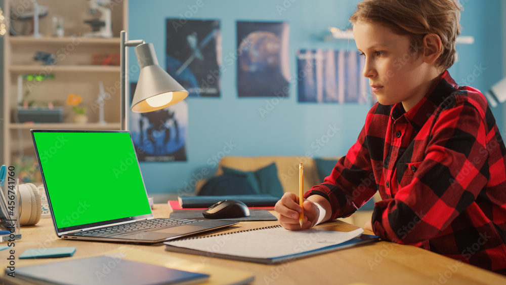 聪明的小男孩在家用绿屏笔记本电脑上网课。快乐少年