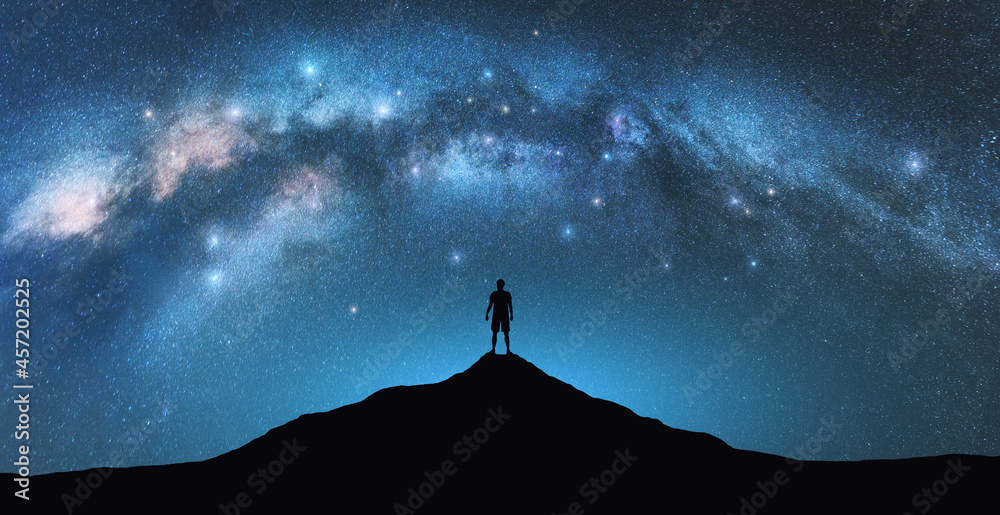 星夜的银河拱门和山顶上的人。独自一人的剪影，蓝天与