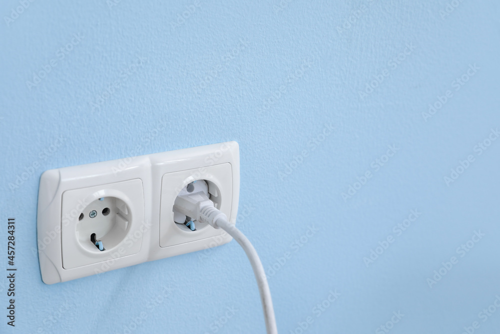 彩色墙上带插头的电气插座