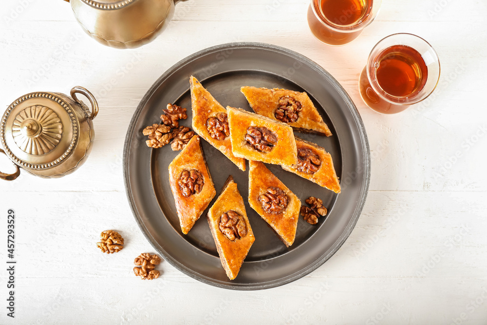Tray with tasty baklava and glasses of Turkish tea on light wooden background