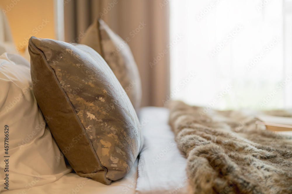 近距离拍摄柔软舒适的卧室枕头，布置在酒店卧室，晨光来自风