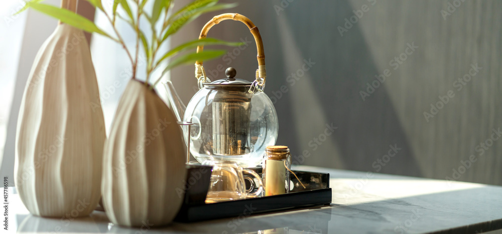 木制茶盘上的玻璃茶壶，大理石餐桌上的白色花瓶，在li有一个遮阳帘