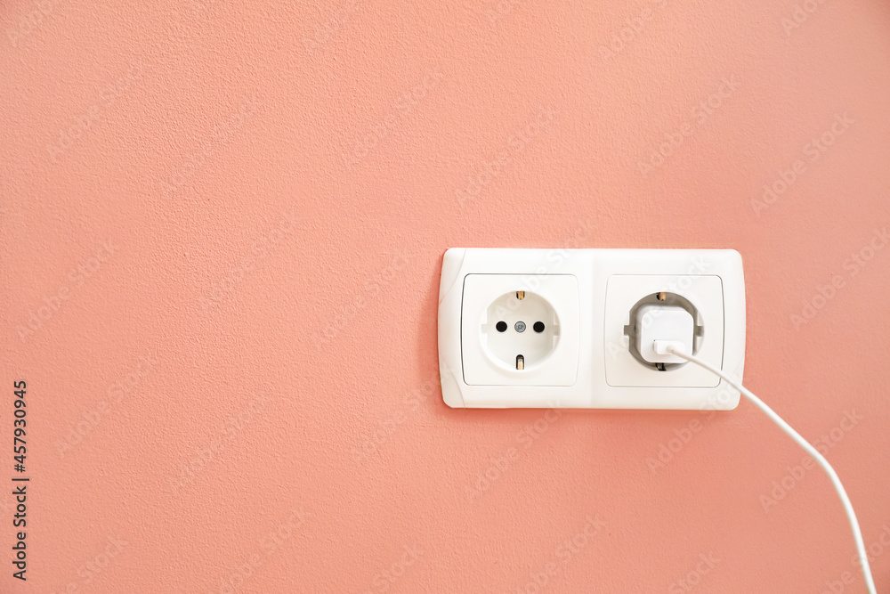 Electric socket with plug on color wall
