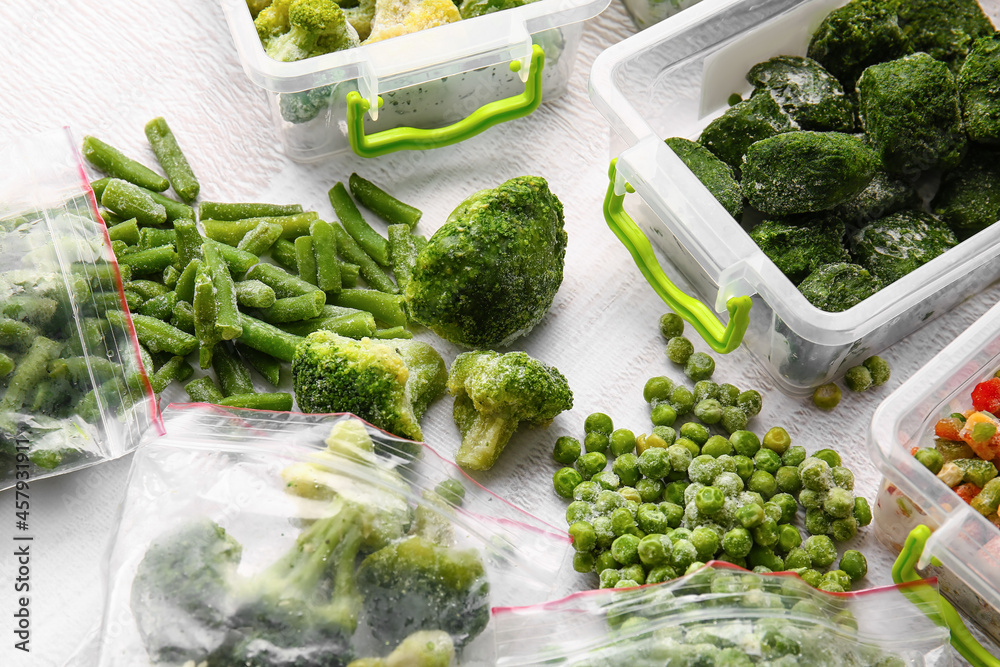塑料容器和塑料袋，在浅色背景下装有不同的冷冻蔬菜