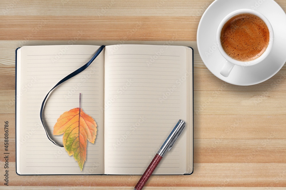 秋天，在一张乡村的木桌上放一本带时尚钢笔的空白日记，里面有一杯茶
