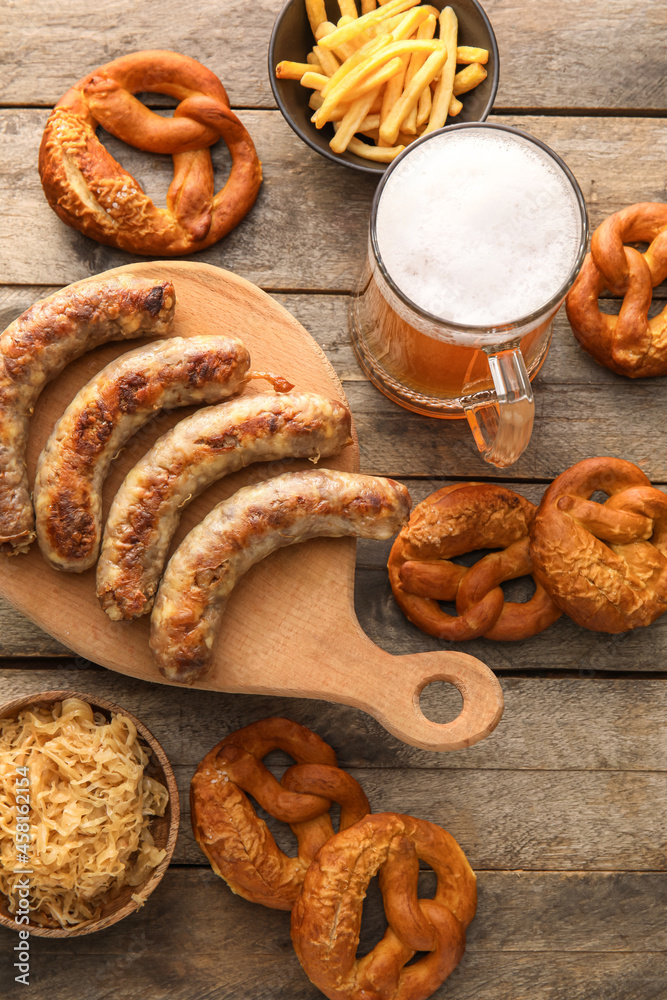Mug of cold beer, board with Bavarian sausages and snacks on wooden background. Oktoberfest celebrat