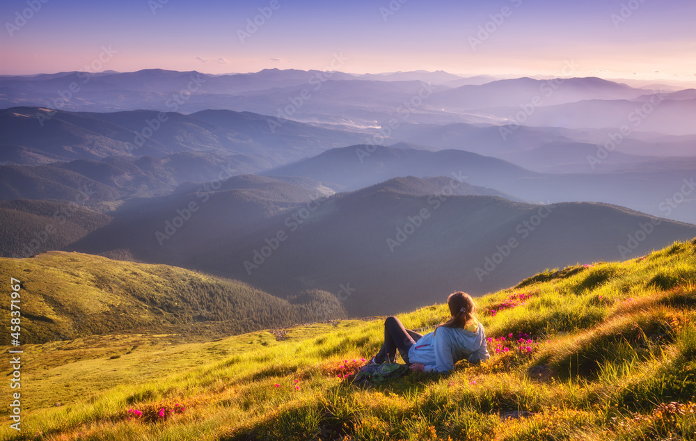 青山上的年轻女子，绿草如茵，粉色花朵，眺望美丽的山脉