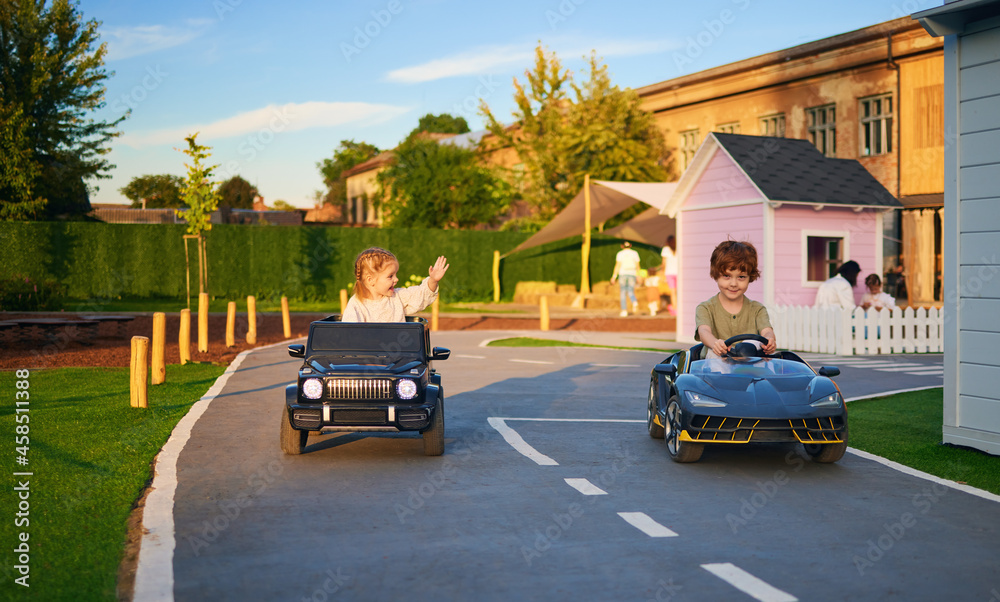 快乐的孩子们开着玩具电动汽车，在操场上玩得很开心