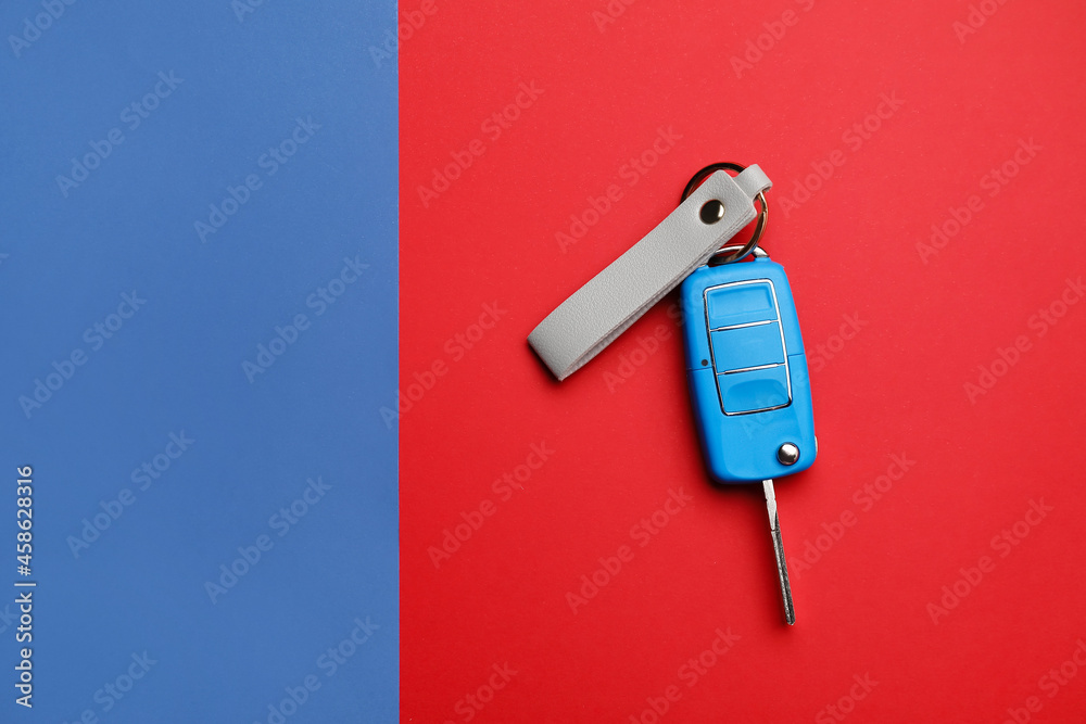 Car key with leather keychain on color background