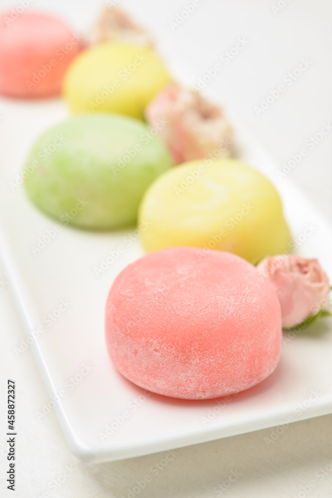 Plate with tasty Japanese mochi and flowers, closeup