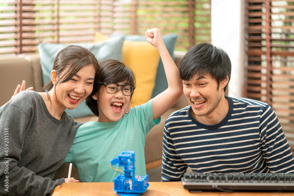 在家学习的概念，亚洲男孩与父亲和母亲在Digital上成功控制机械臂
