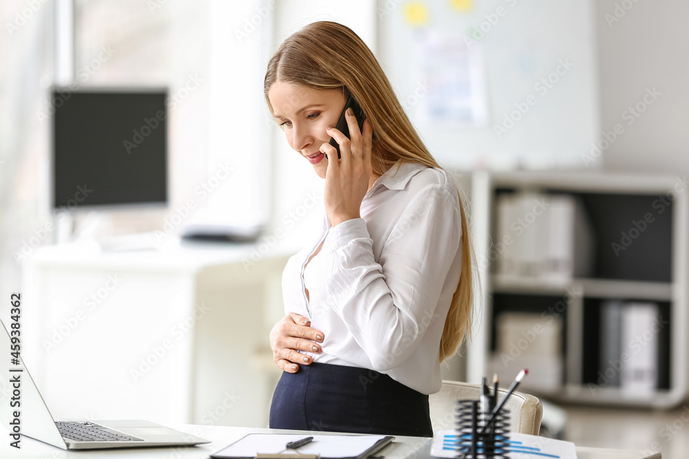 怀孕的女商人在办公室用手机聊天