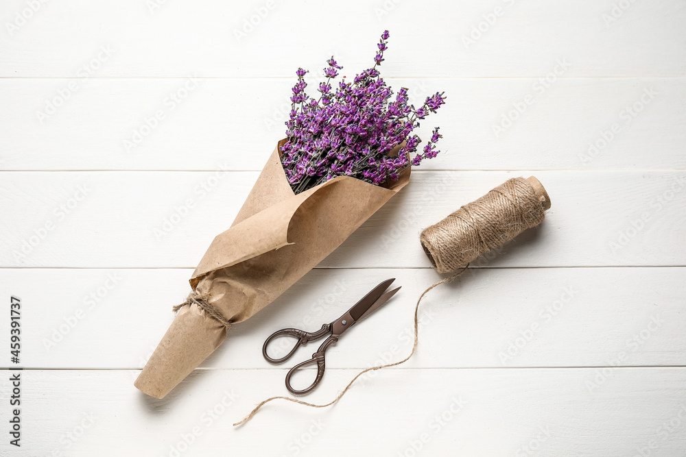 淡紫色花朵、剪刀和绳子在浅色木质背景上的花束