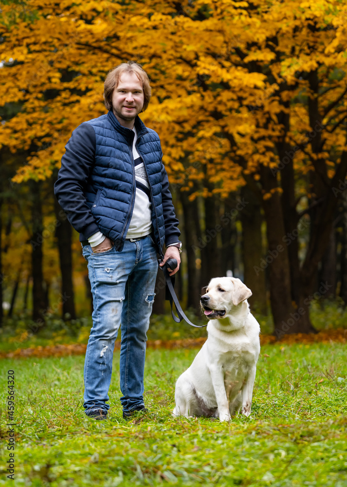 一名男子和一只小狗散步时看着镜头。金色的奇妙秋季公园。Fu