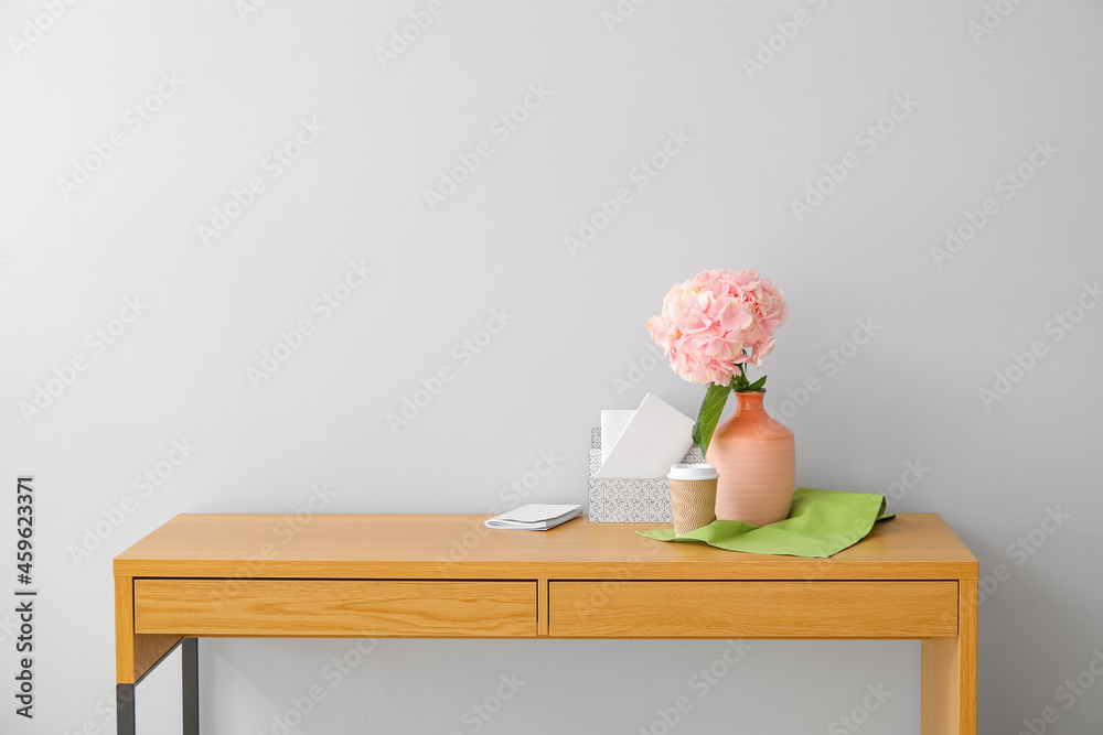 桌子上靠近灯光墙的花瓶，花瓶上有绣球花和整理器
