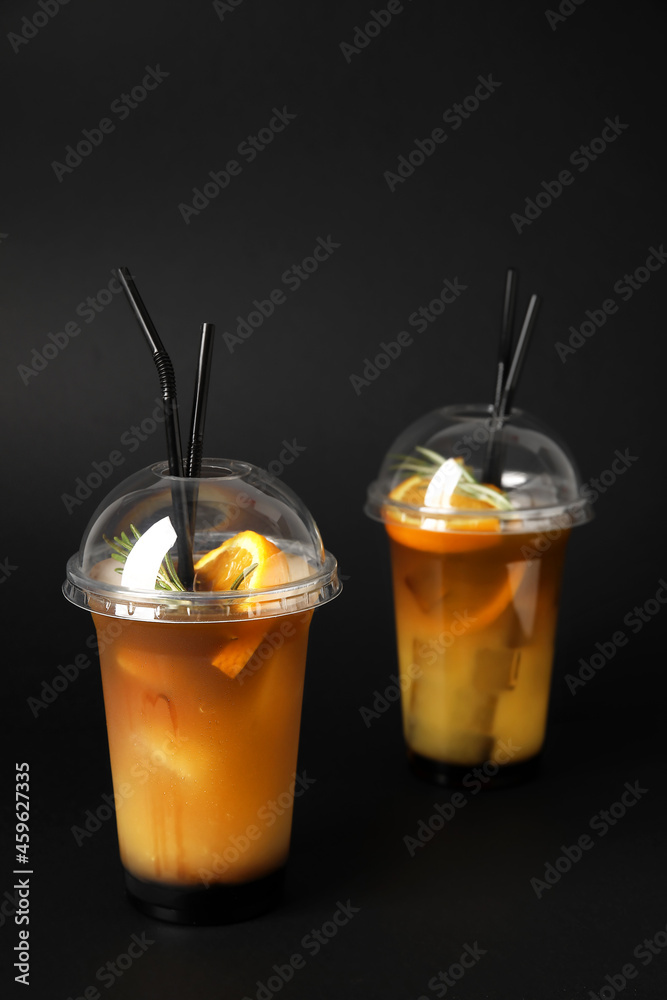 深色背景下的带橙汁的美味咖啡塑料杯