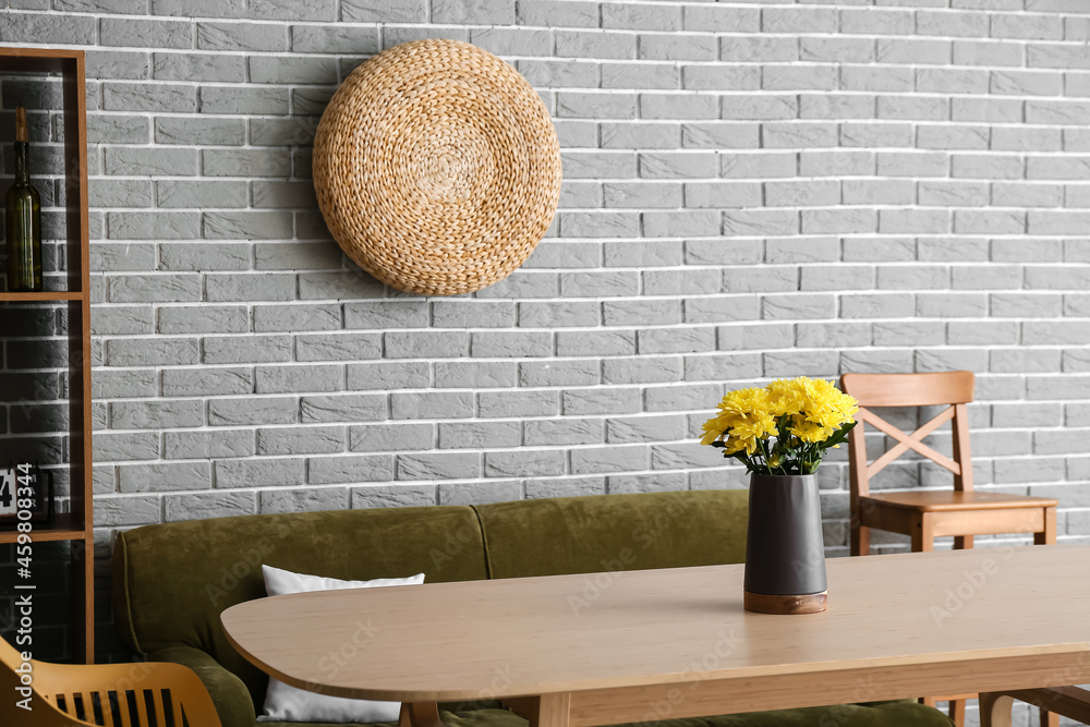 现代厨房内部配有菊花花瓶和舒适的绿色沙发的木制餐桌