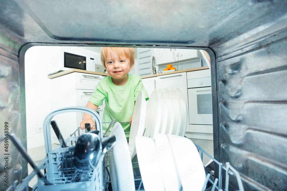 Little blond toddler take dishes from dishwasher