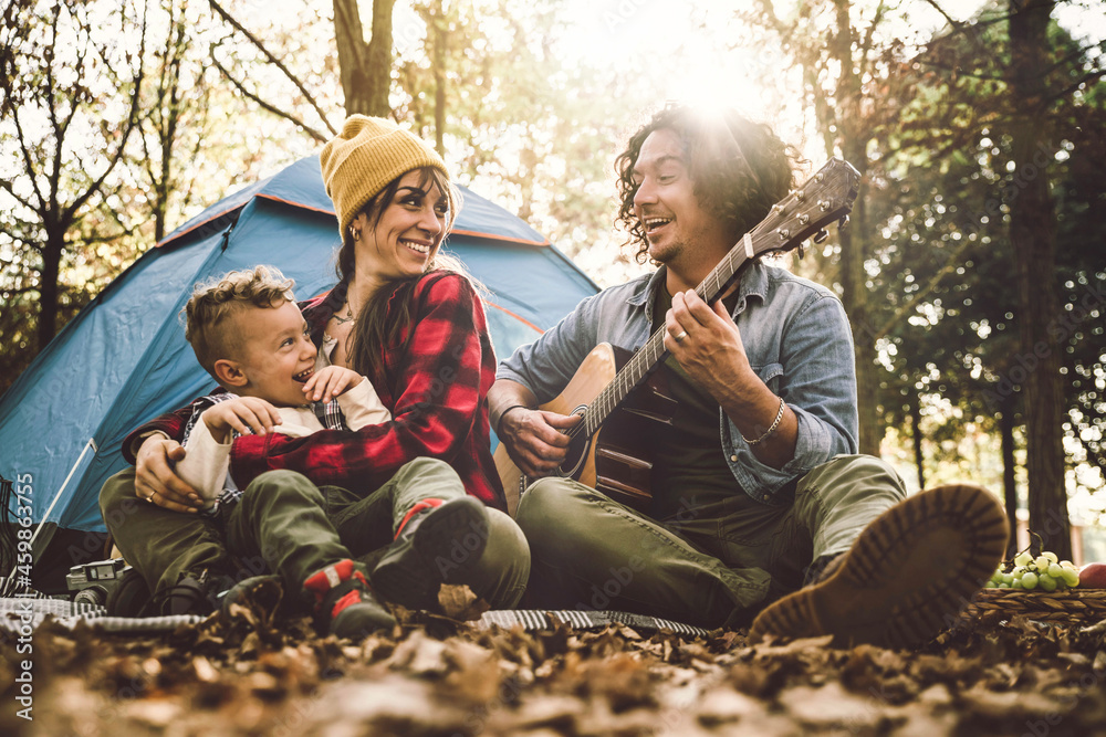 快乐的一家人在森林里露营，一起弹吉他唱歌——妈妈、爸爸和儿子哈维