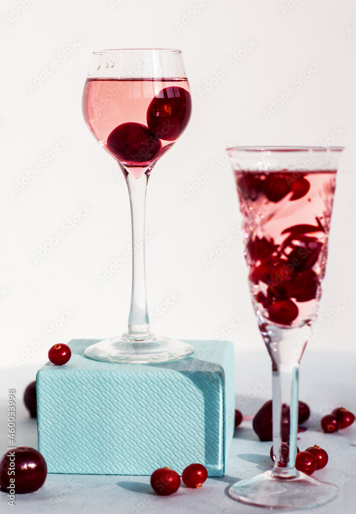一个长柄玻璃杯，上面放着樱桃利口酒或任何红色酒精鸡尾酒，放在蓝色的盒子底座上，