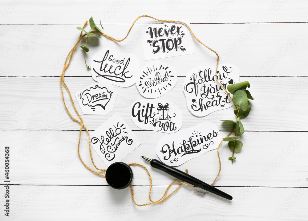 Paper pieces with different text and nib pen on white wooden background