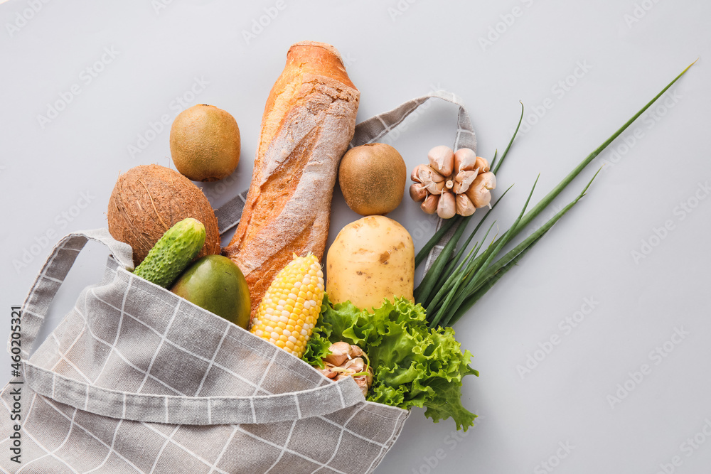 浅色背景下有水果、蔬菜、绿色蔬菜和面包的环保袋