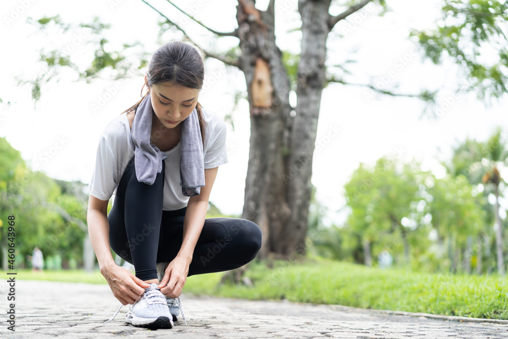 亚洲运动美女在公园跑步前系鞋带。