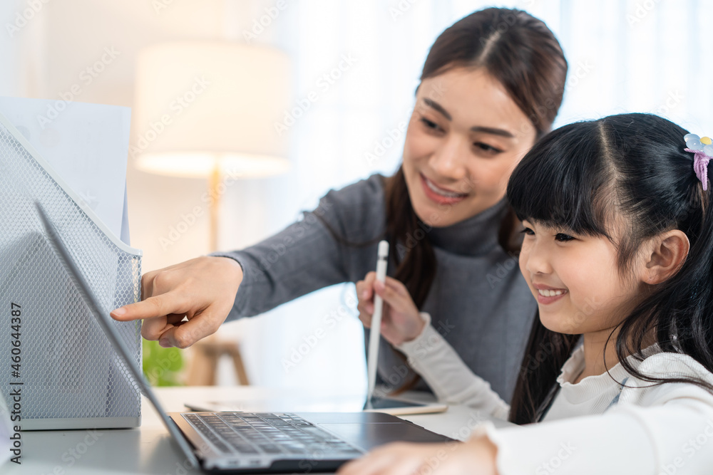 亚洲小女孩在家和妈妈一起学习网课。