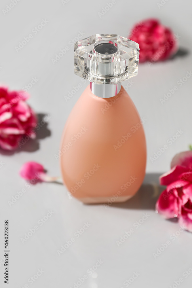 淡背景下的一瓶香水和康乃馨花