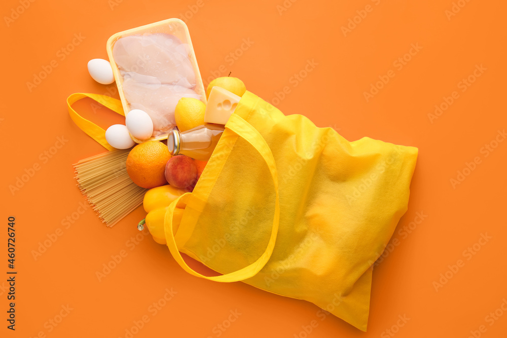 Eco bag with different products and bottle of juice on color background