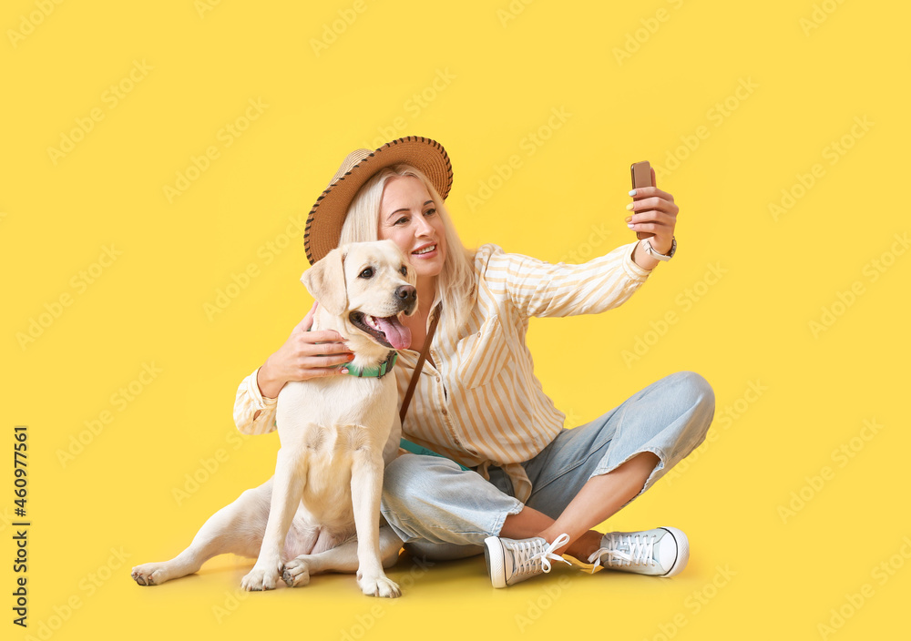 成熟的女人和可爱的拉布拉多犬在黄色背景下自拍