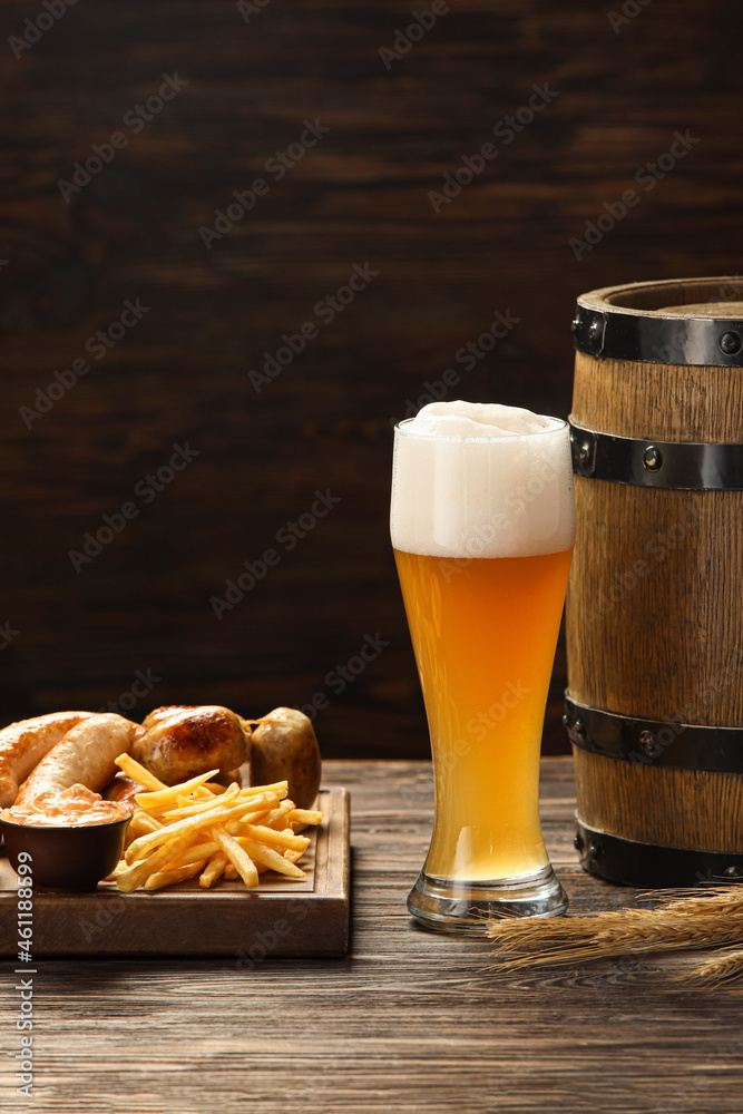 Glass of cold beer, wooden board with Bavarian sausages and snacks on table. Oktoberfest celebration