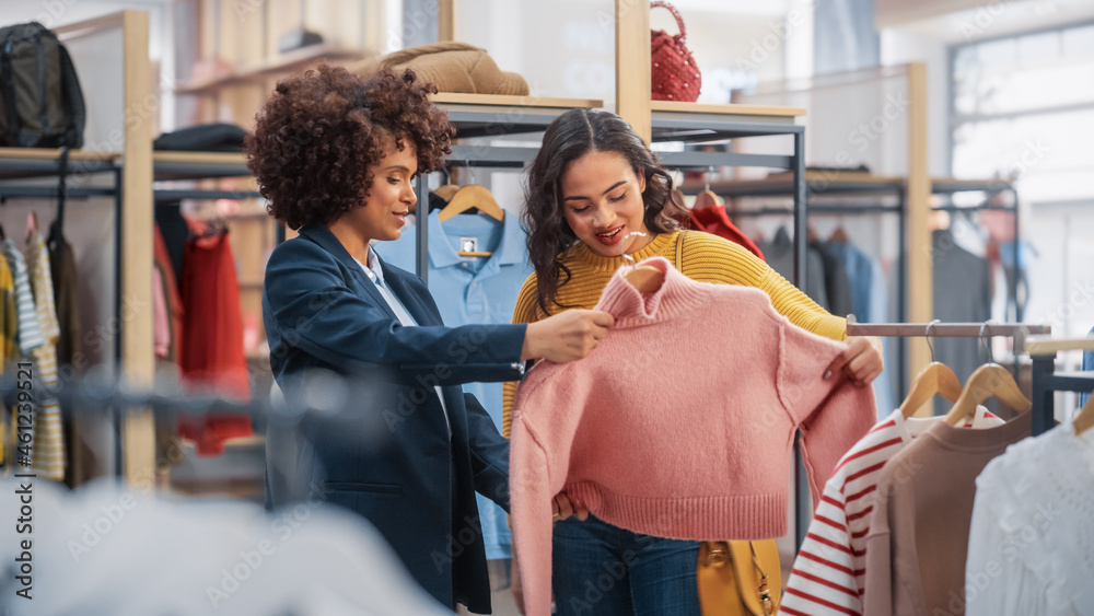 年轻女性顾客在服装店购物，零售助理帮助提供建议。多样化