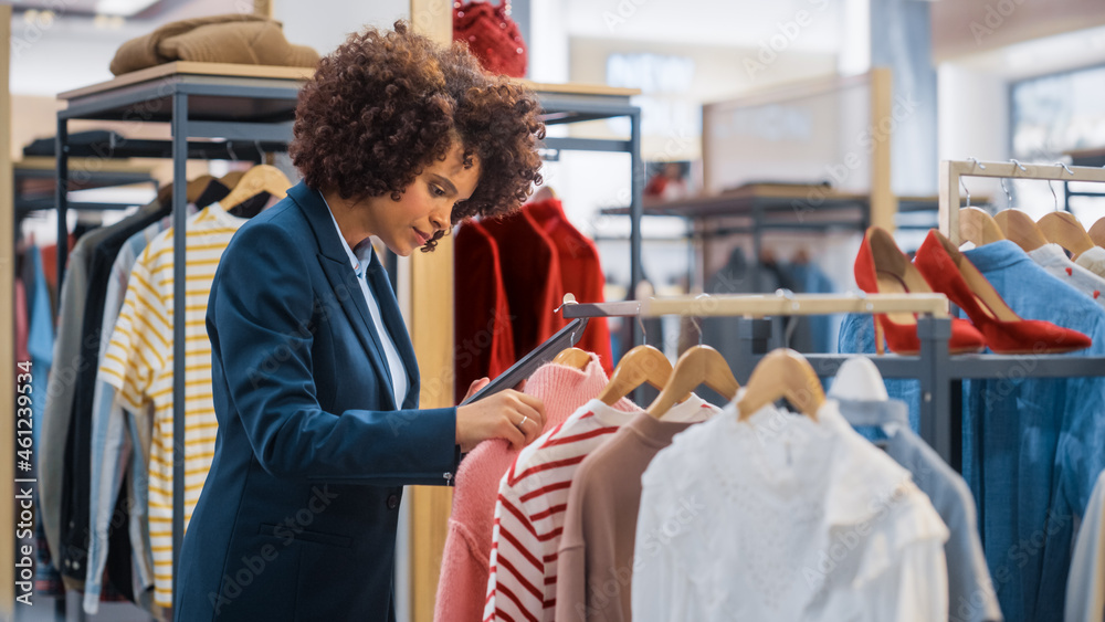 服装店：女性销售经理使用平板电脑打造时尚时装系列