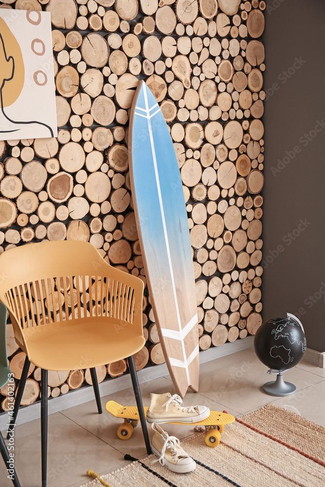 现代时尚房间的内部，靠近木墙，配有冲浪板和椅子