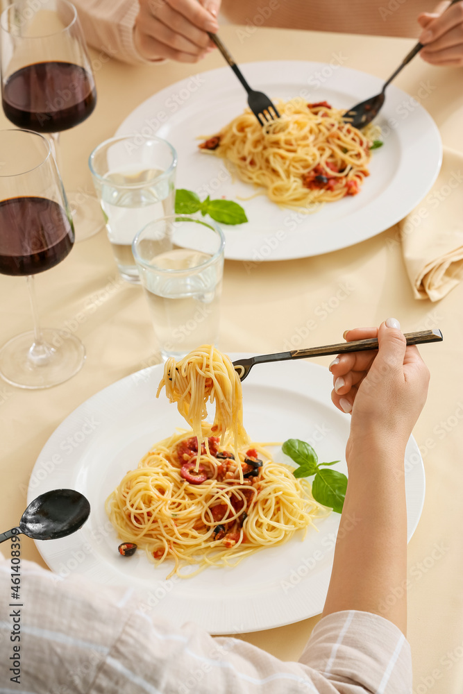 女人在餐厅的餐桌上吃美味的Pasta Puttanesca