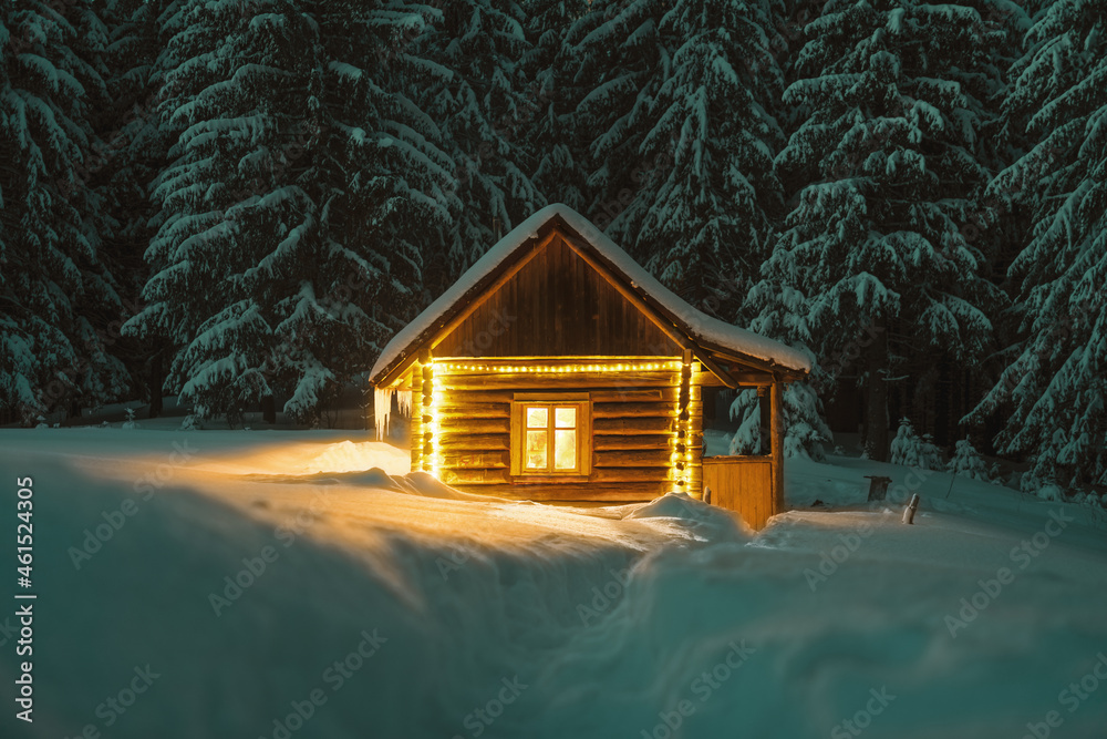 梦幻般的冬季景观，在白雪皑皑的森林中有发光的木屋。喀尔巴阡山脉的舒适房子