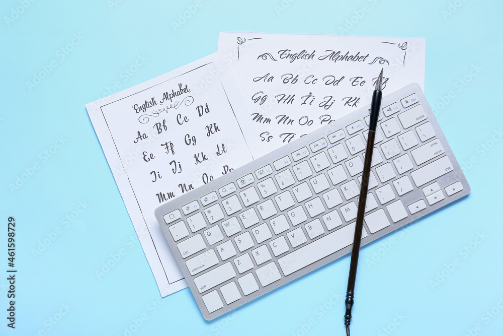 蓝底带字母表、电脑键盘和画笔的纸张