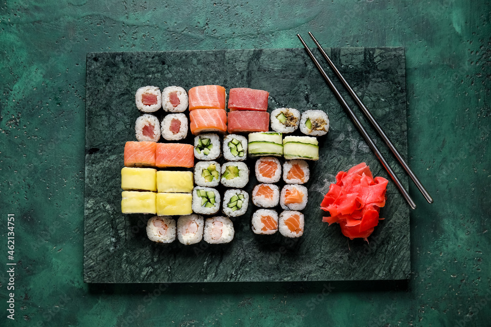 木板上有一套美味的寿司卷、筷子和生姜，颜色为背景
