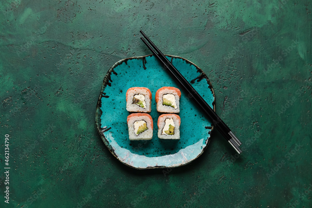 时尚的盘子，背景是美味的寿司卷和筷子