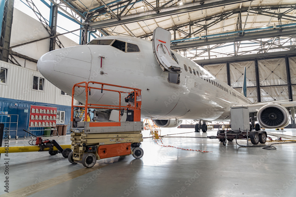 大型白色客机在室内机场机库进行维修检查。飞机概念